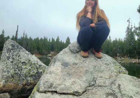 Faith sits on a rock by a lake in Grand Teton National Park